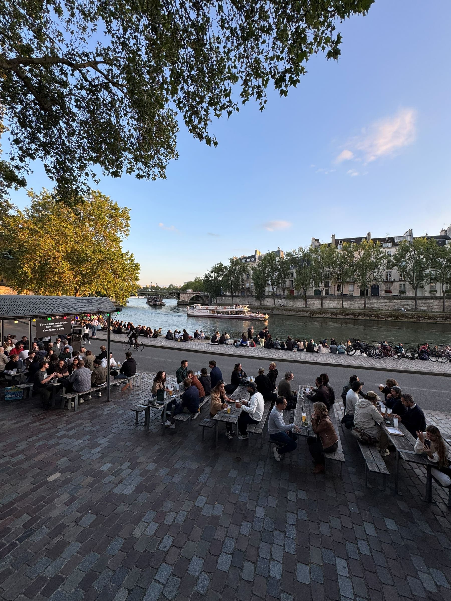 Parisians sitting along the Seine quay in the evening