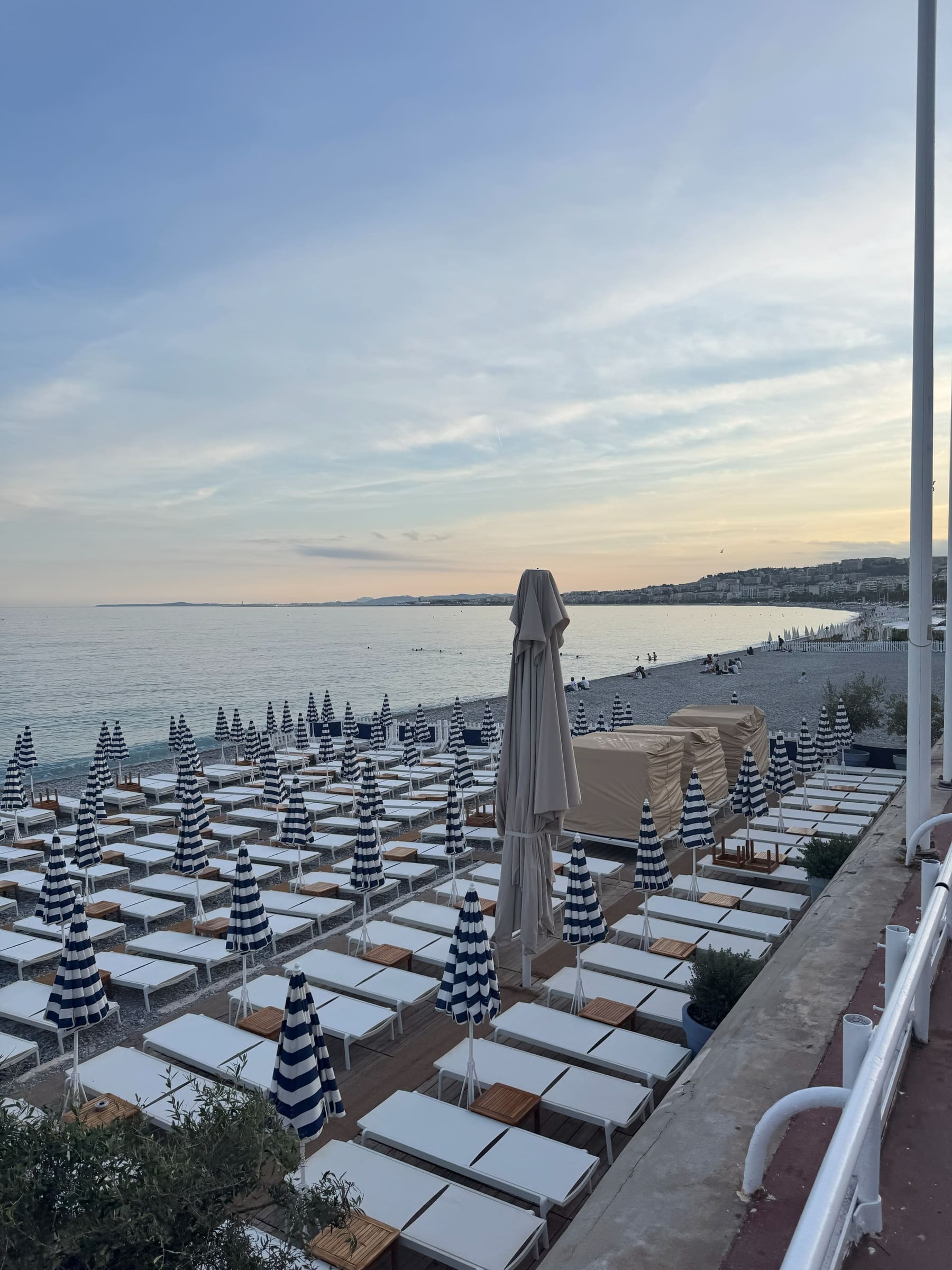 The Promenade des Anglais at dusk with striped parasols along the beach