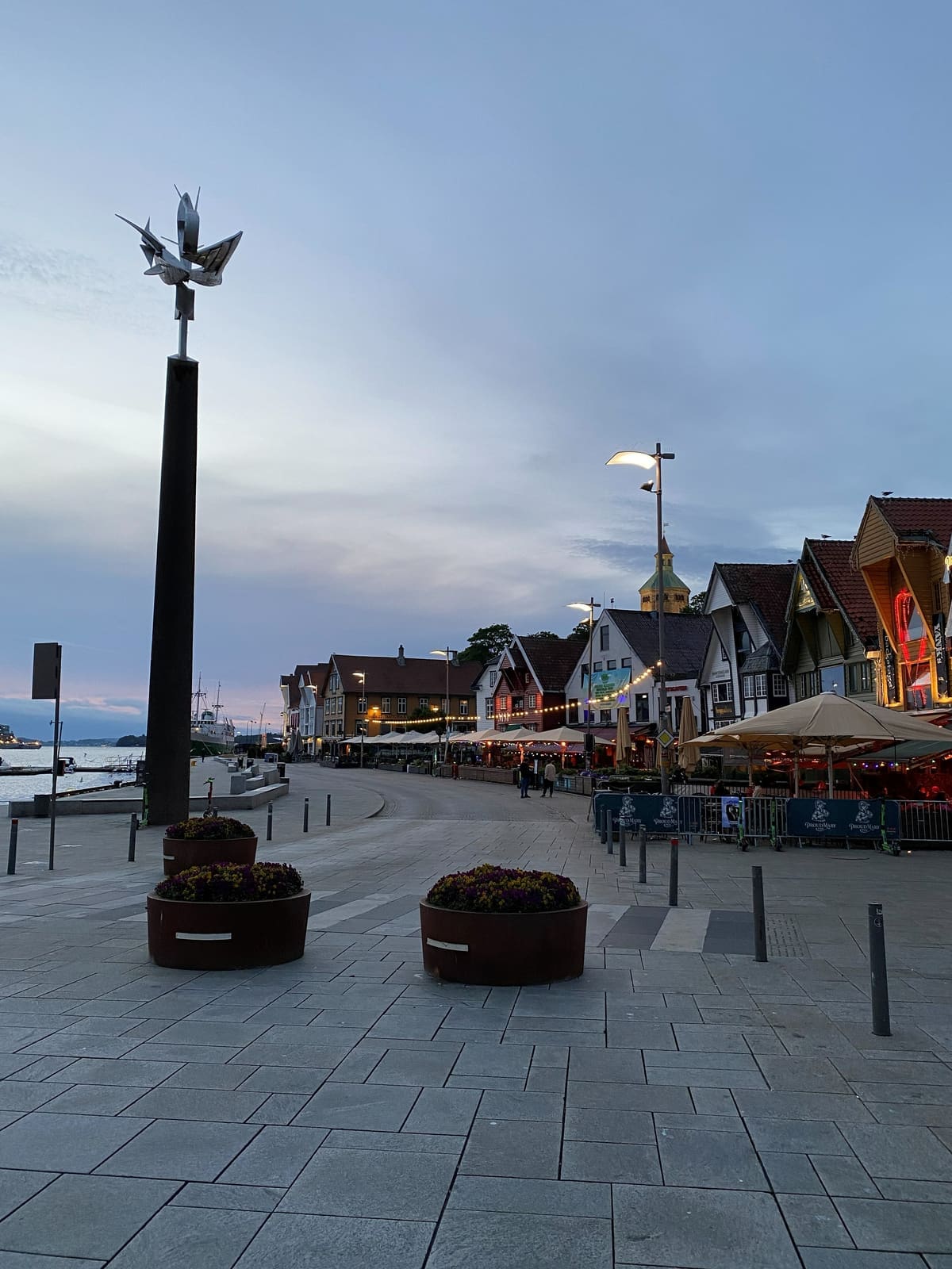 The harbour front at dusk with wooden buildings and lit windows