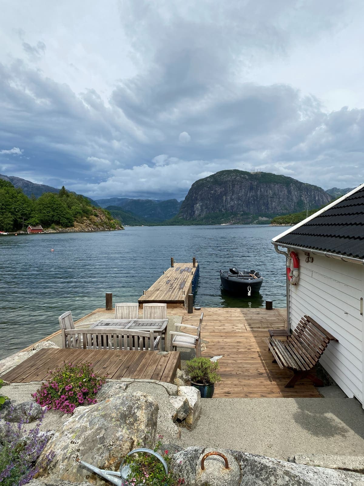 A wooden jetty on a still fjord with a mountain face behind