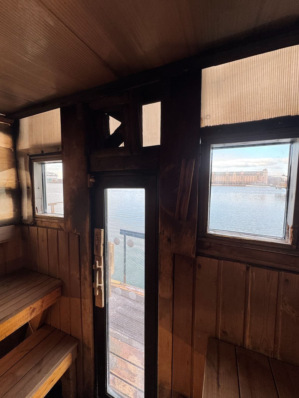 Inside a floating sauna in Oslo, benches and a door open onto the fjord