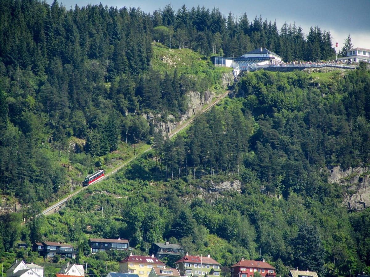 A red funicular car climbing the wooded hillside above Bergen to the station at the top