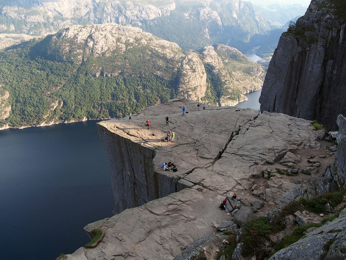 The flat rock plateau of Preikestolen with walkers on it, high above the Lysefjord